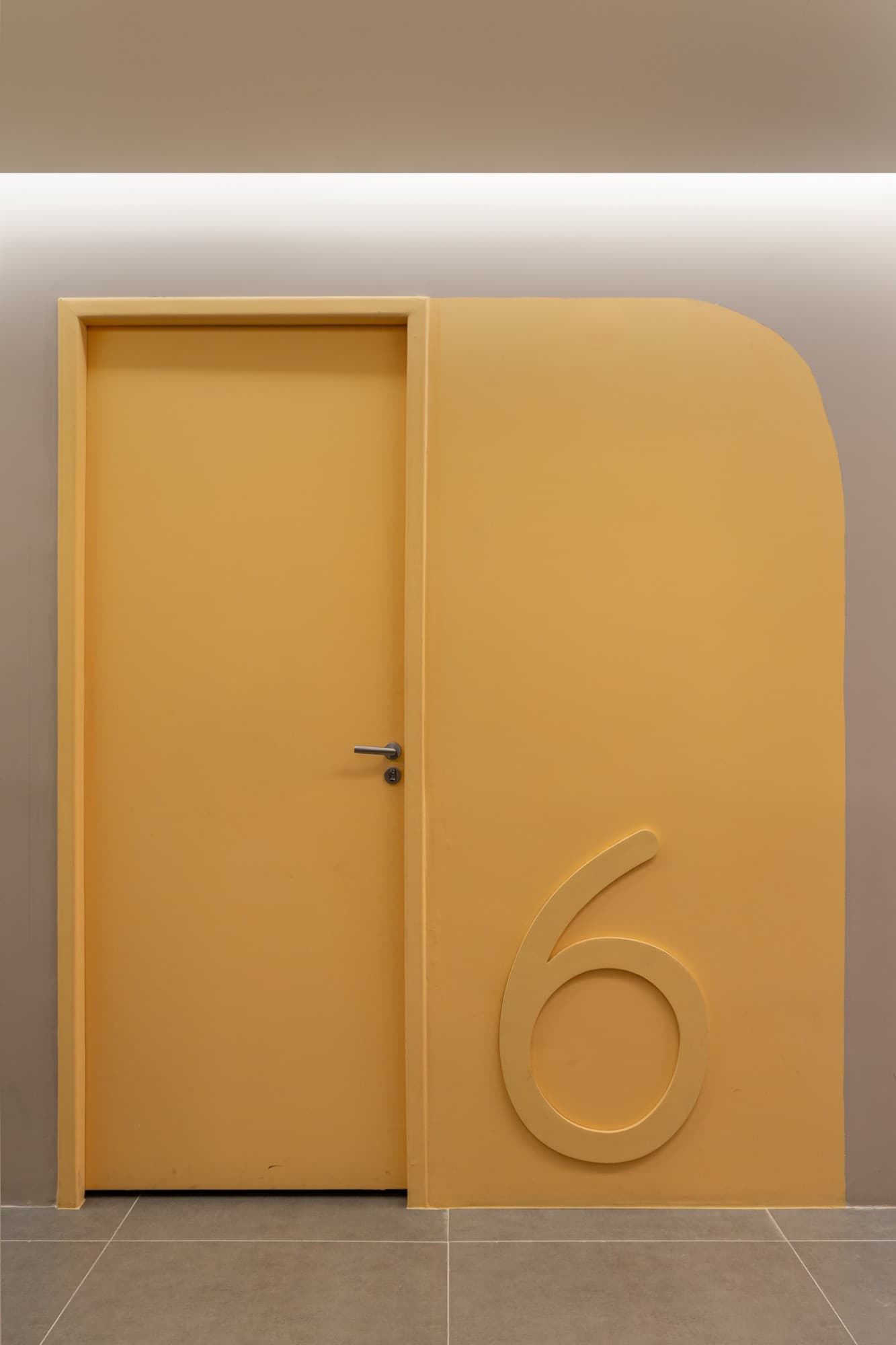 Porta amarela de consultório com o número 6 em relevo